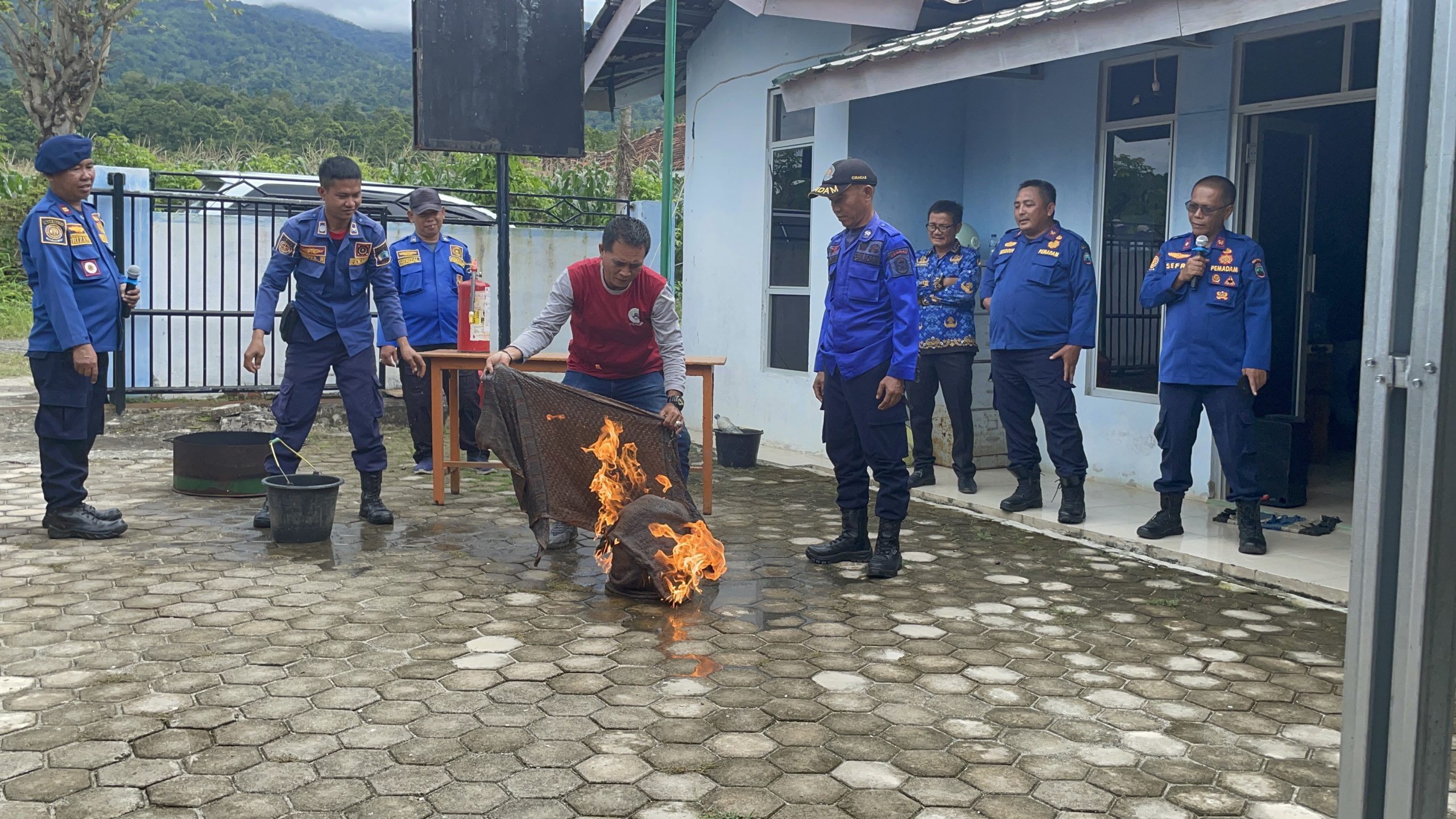 Sejumlah pemadam kebakaran sedang memeragakan penanganan kebakaran dengan menutup gas terbakar memakai goni basah