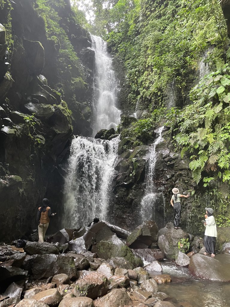 Tiga pengunjung air terjun 9 puteri sedang bermain air di sekitar kawasan air terjun