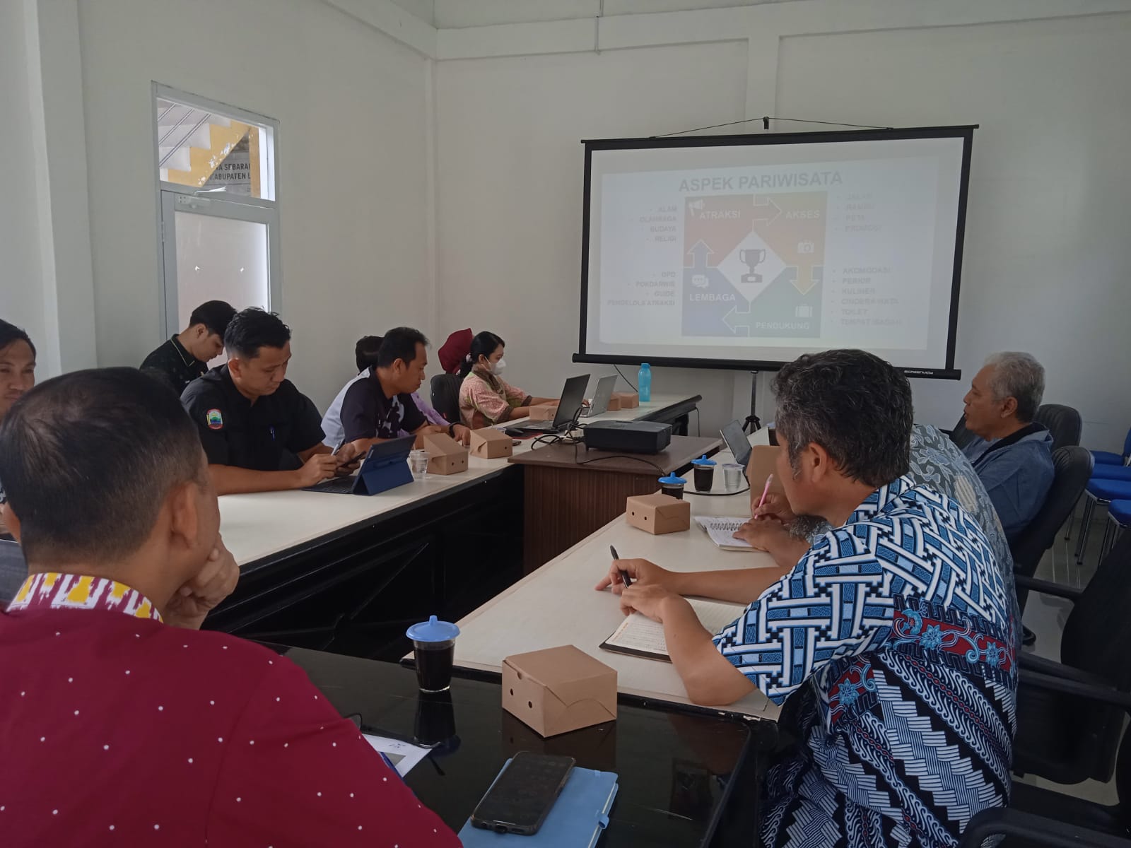Foto perwakilan Bappeda Lampung Selatan dan tim Paluma Nusantara sedang duduk melingkar di satu ruangan sambil mennghadap layar di depan
