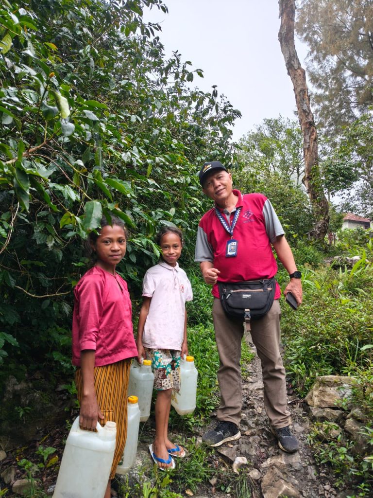 Dua anak membawa jirigen berfoto bersama salah satu tim Paluma
