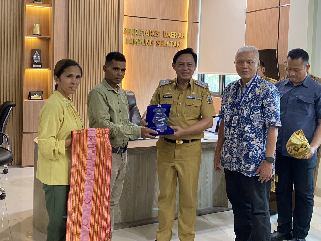Sejumlah tamu dan aparatur pemerintah daerah berdiri bersama di ruang Kantor Sekretaris Daerah Lampung Selatan. Perwakilan delegasi internasional menyerahkan cendera mata kepada Sekretaris Daerah dalam suasana formal dan penuh keakraban.